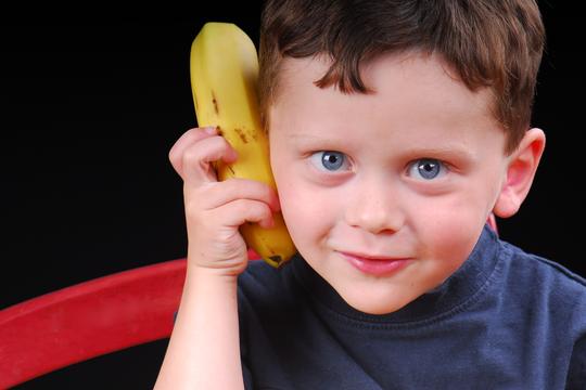 dječak drži bananu na uhu